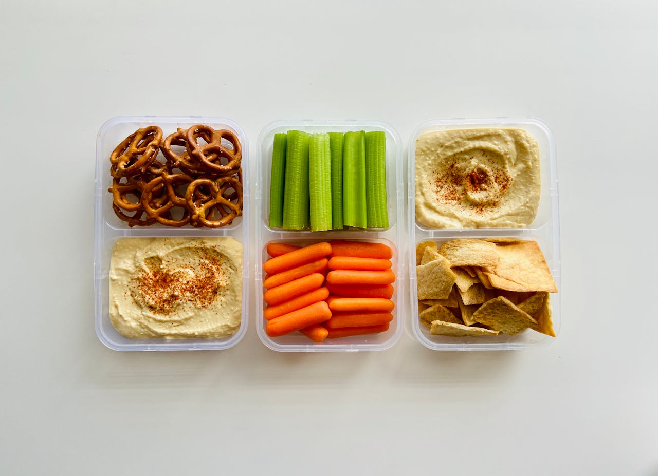 hero-img-01 A fresh and healthy snack platter with hummus, vegetables, and pretzels.